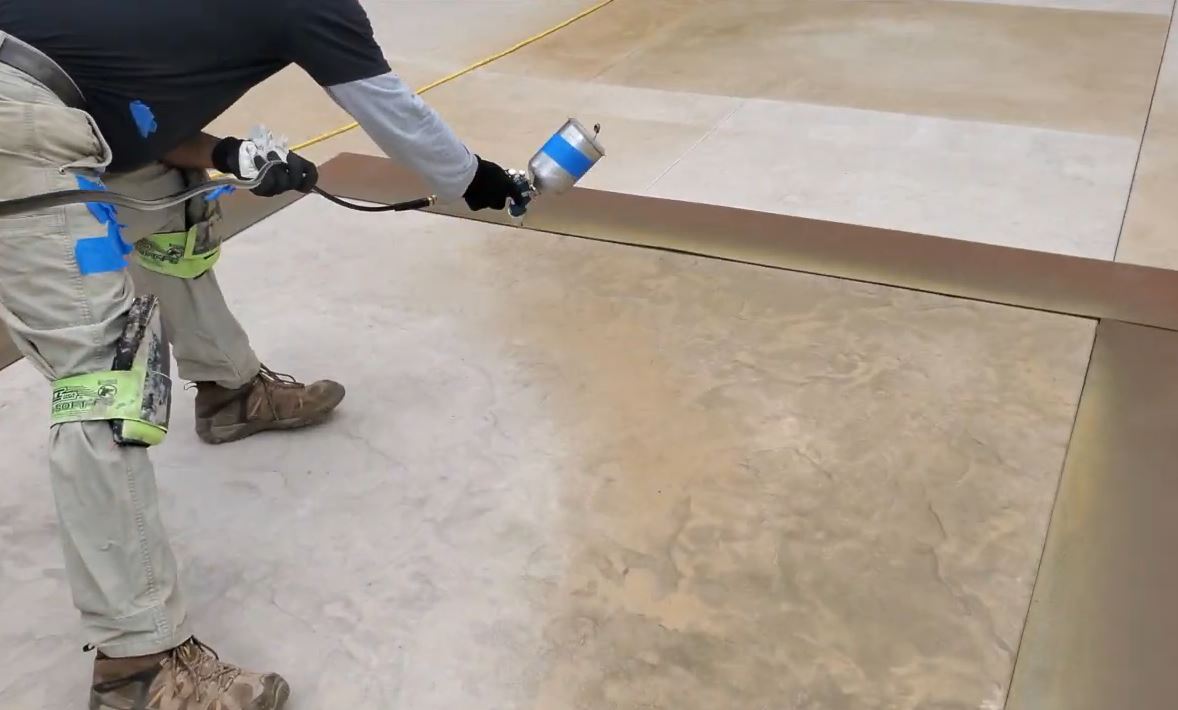concrete contractor applying decorative stain sealant with sprayer
